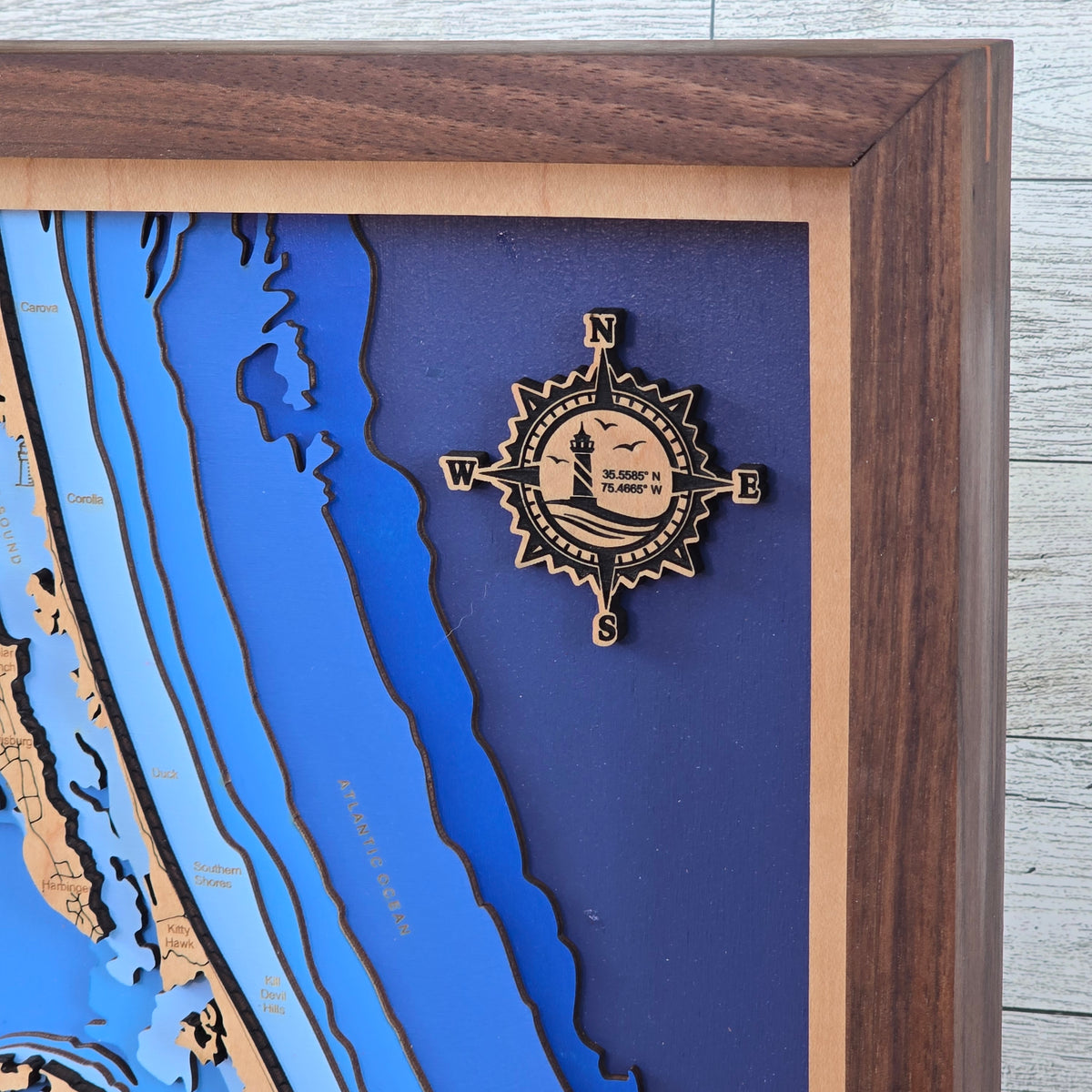 Wooden framed nautical chart with a compass rose on a blue background
