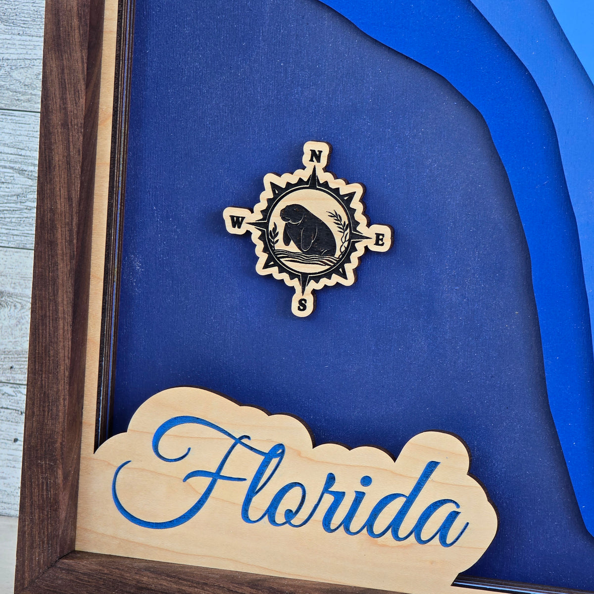 Wooden compass rose with manatee engraved and 'Florida' sign on a blue background