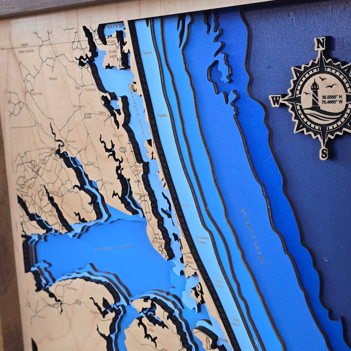 Topographic map with blue water and beige land features, featuring a compass rose at the top.