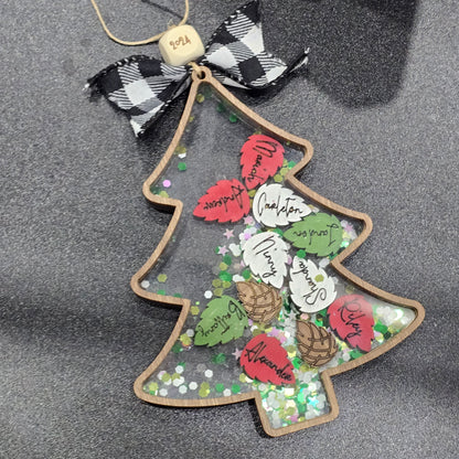 Christmas Tree wooden outline with clear acrylic top. inside is pinecone shapes engraved with names and chunky green and gold glitter. Pinecones are painted red, silver, green and stained brown