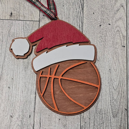 Wooden cutout of a basketball, with a santa hat on a wooden surface