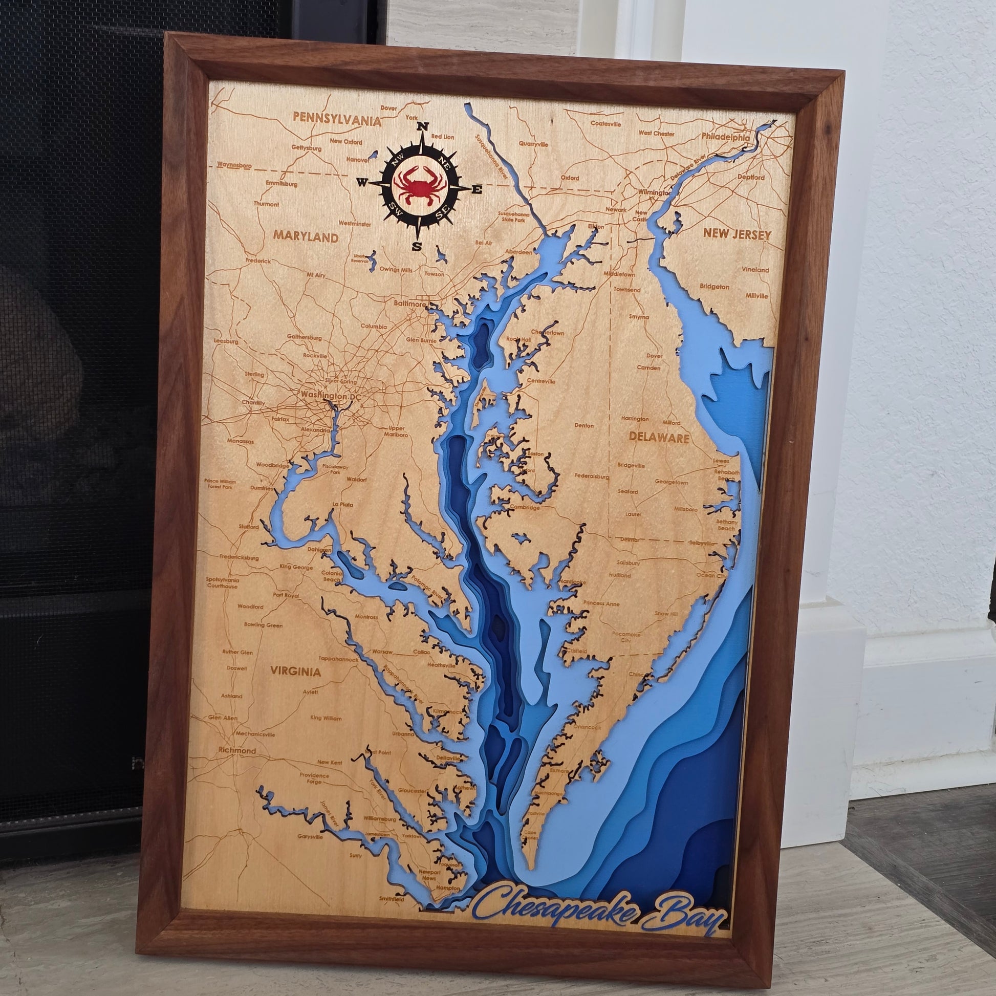 3D bathymetric map of the Chesapeake Bay from Virginia to Pennsylvania with wooden frame and 'Chesapeake Bay' label. Compass rose contains a Red Crab
