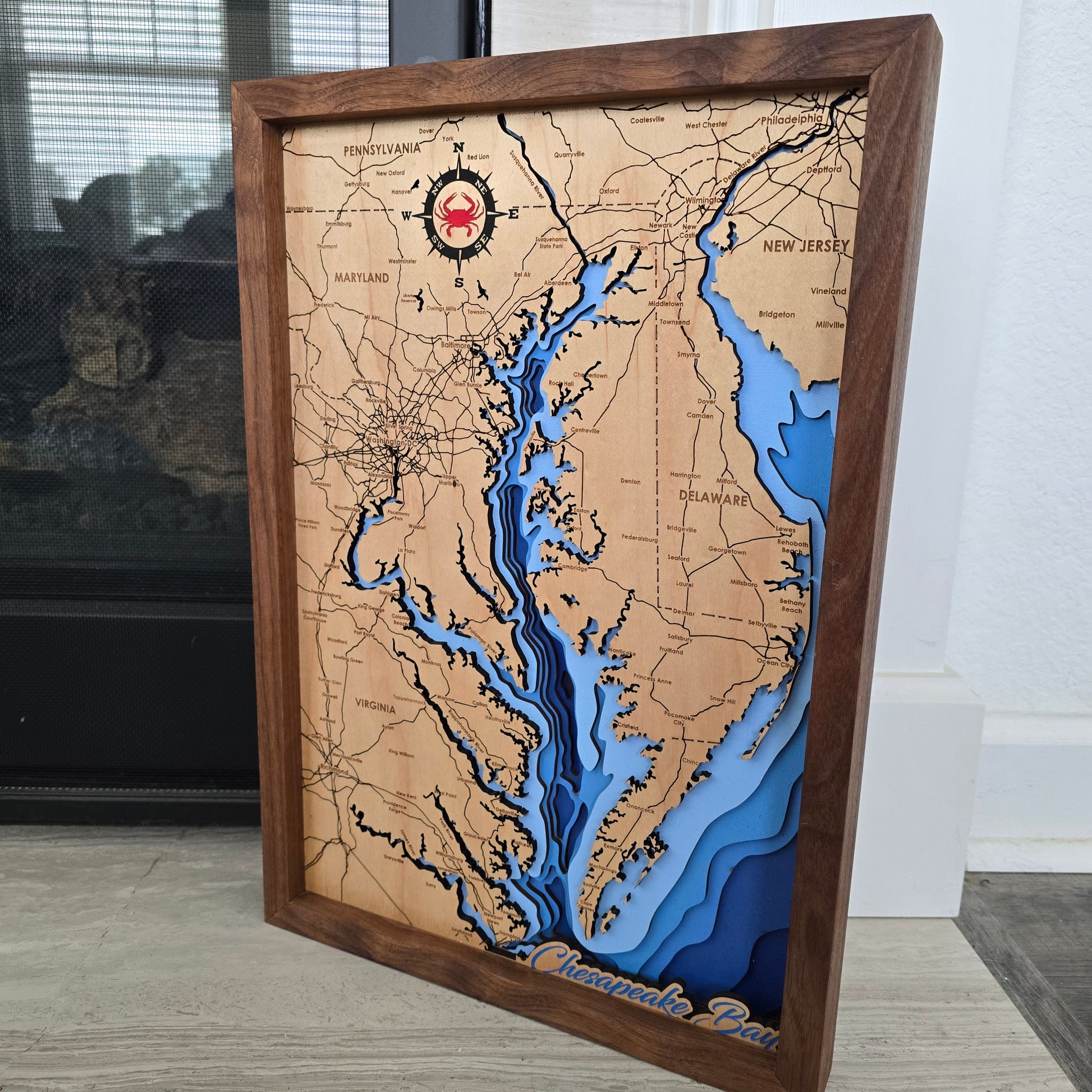 Wooden map with topographic details in a brown frame on a wall.