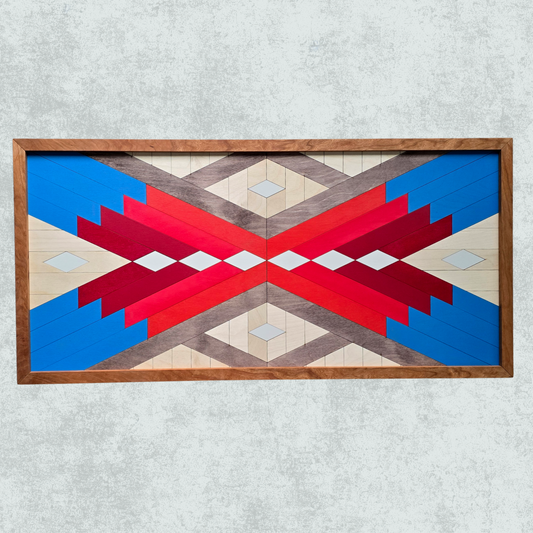 Geometric patterned wall art with red, blue, and beige colors in a wooden frame on a light gray background.
