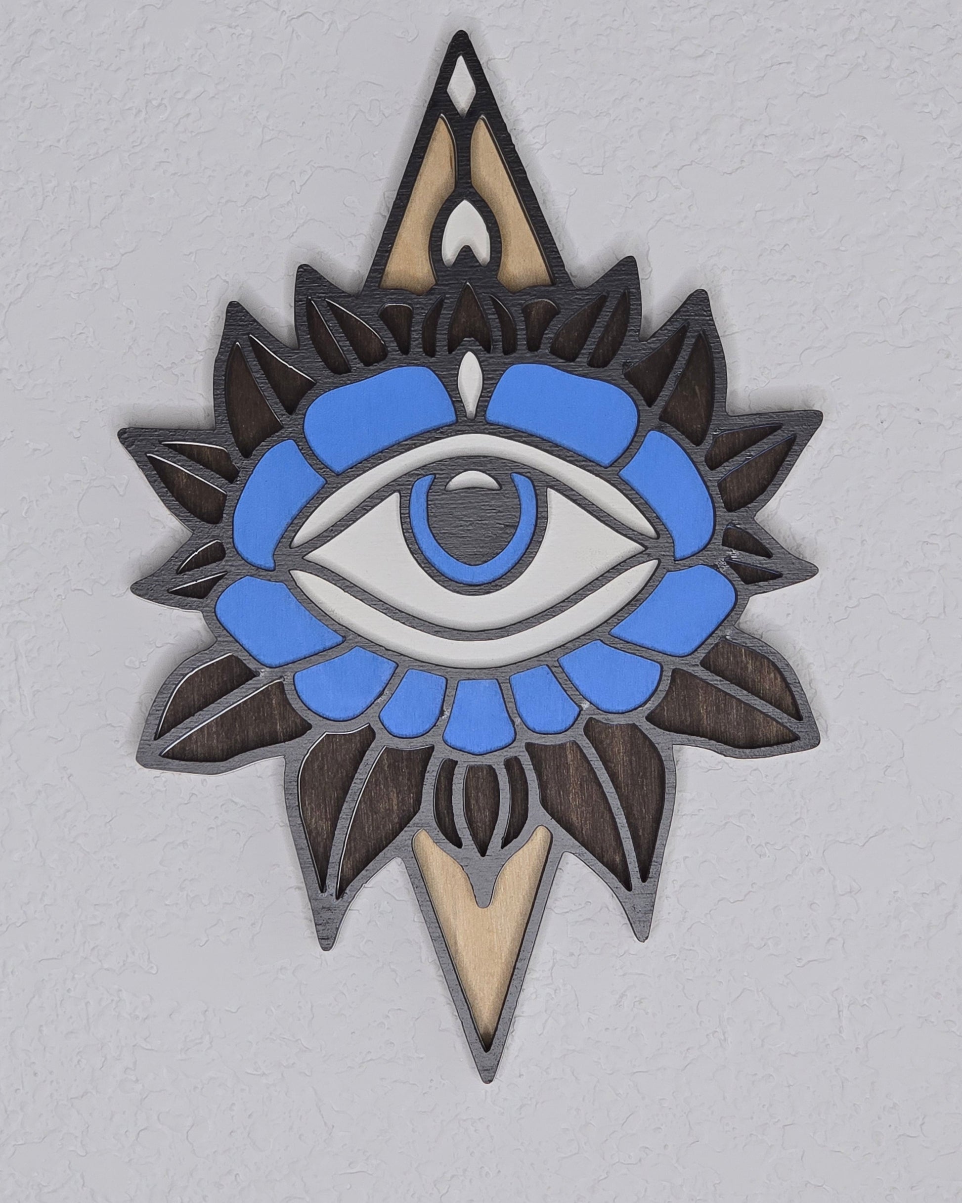 Decorative wall hanging with layered eye and flower design on a gray background