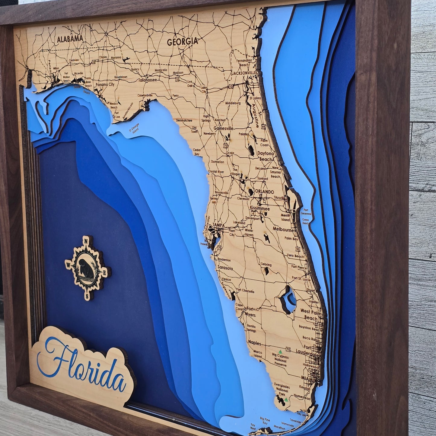 3D bathymetric map of Florida with wooden frame and 'Florida' label with a manatee in the compass rose