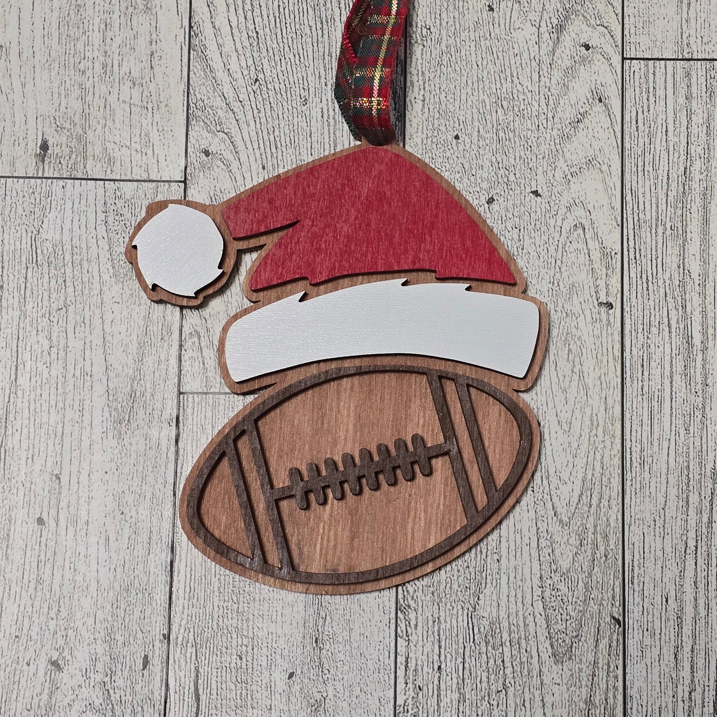 Wooden cutout of a Santa hat and football on a wooden surface