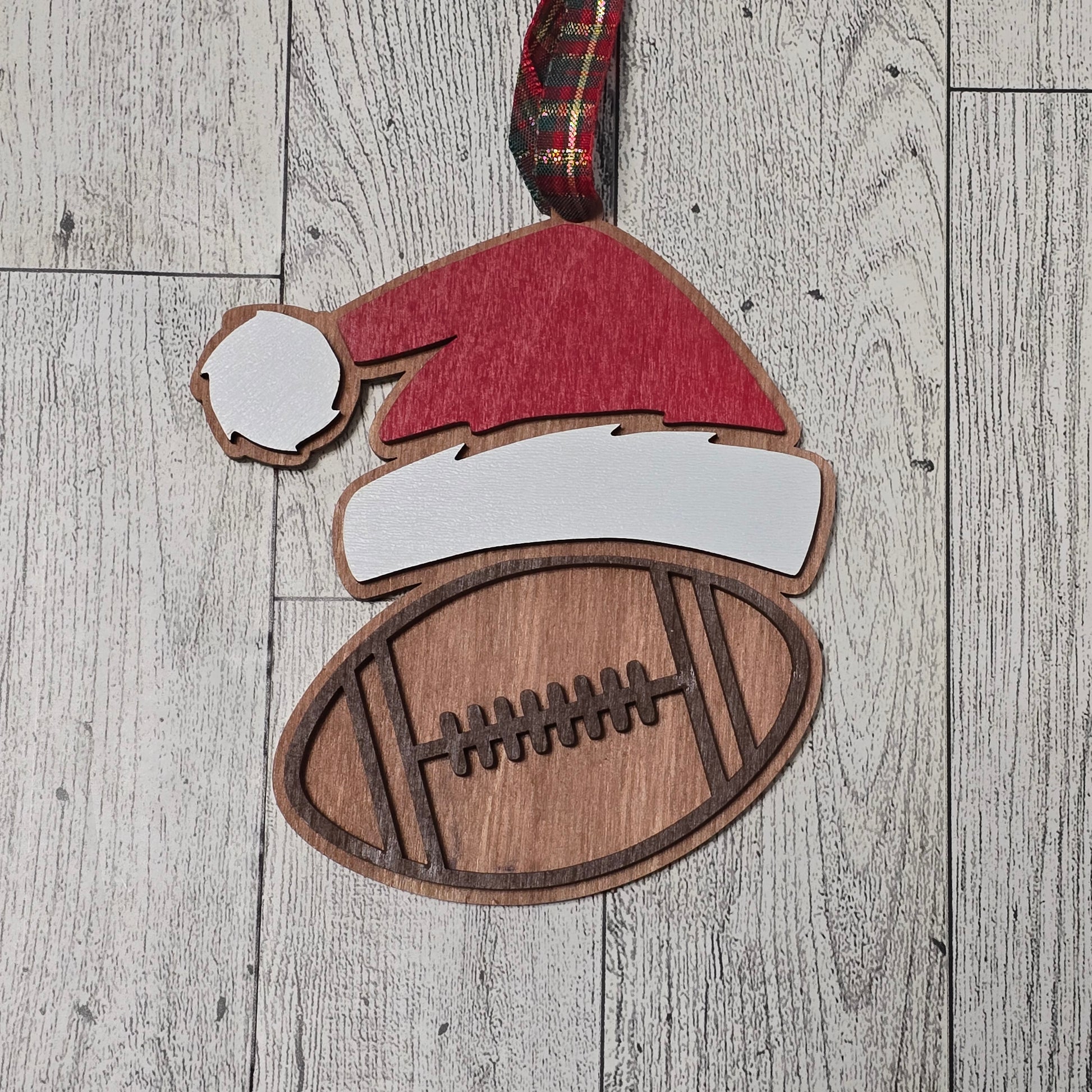 Wooden cutout of a Santa hat and football on a wooden surface