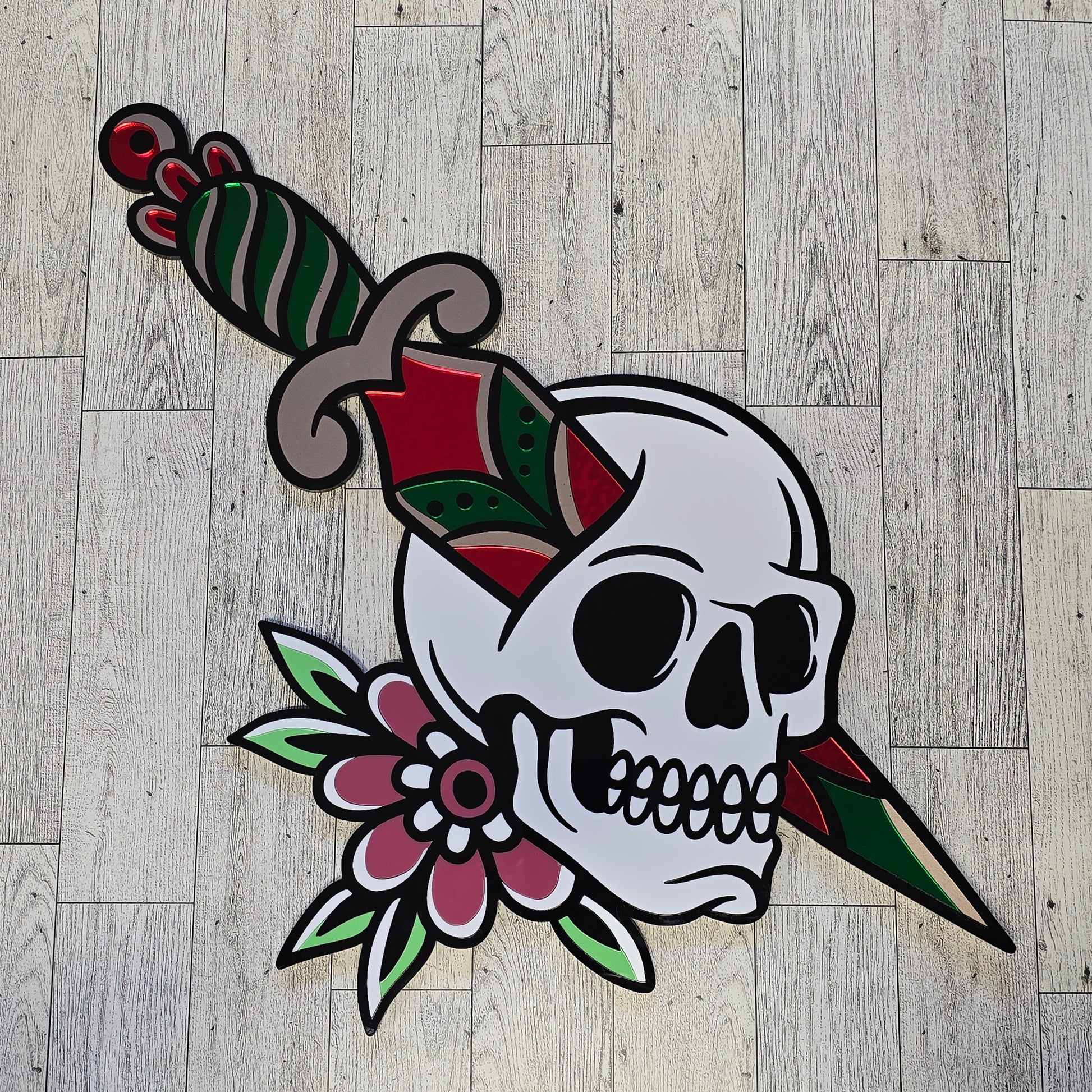 Decorative skull design with flowers and knife through skull on a wooden floor.