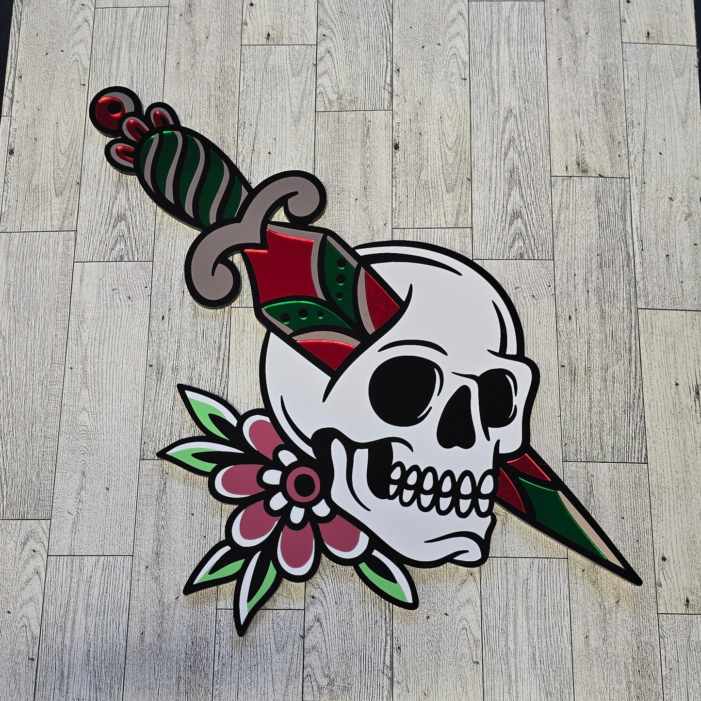Decorative skull design with flowers and knife through skull on a wooden floor.