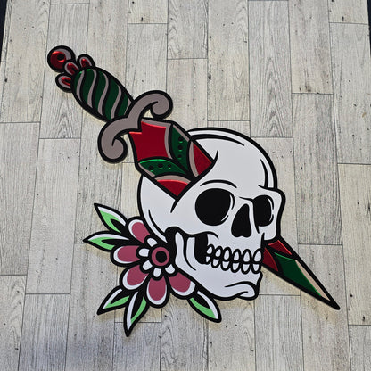 Decorative skull design with flowers and knife through skull on a wooden floor.