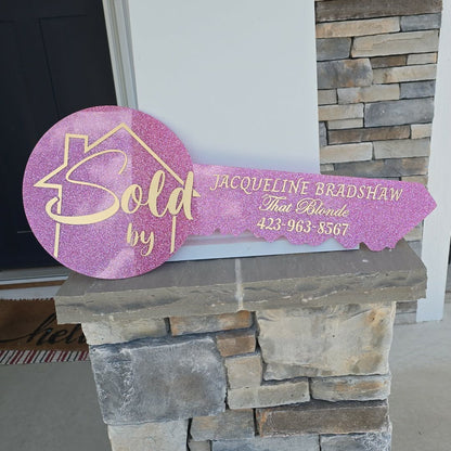 Pink glitter key outline with a house outline and "sold by" in the base of the key, and realtor info in the key portion.