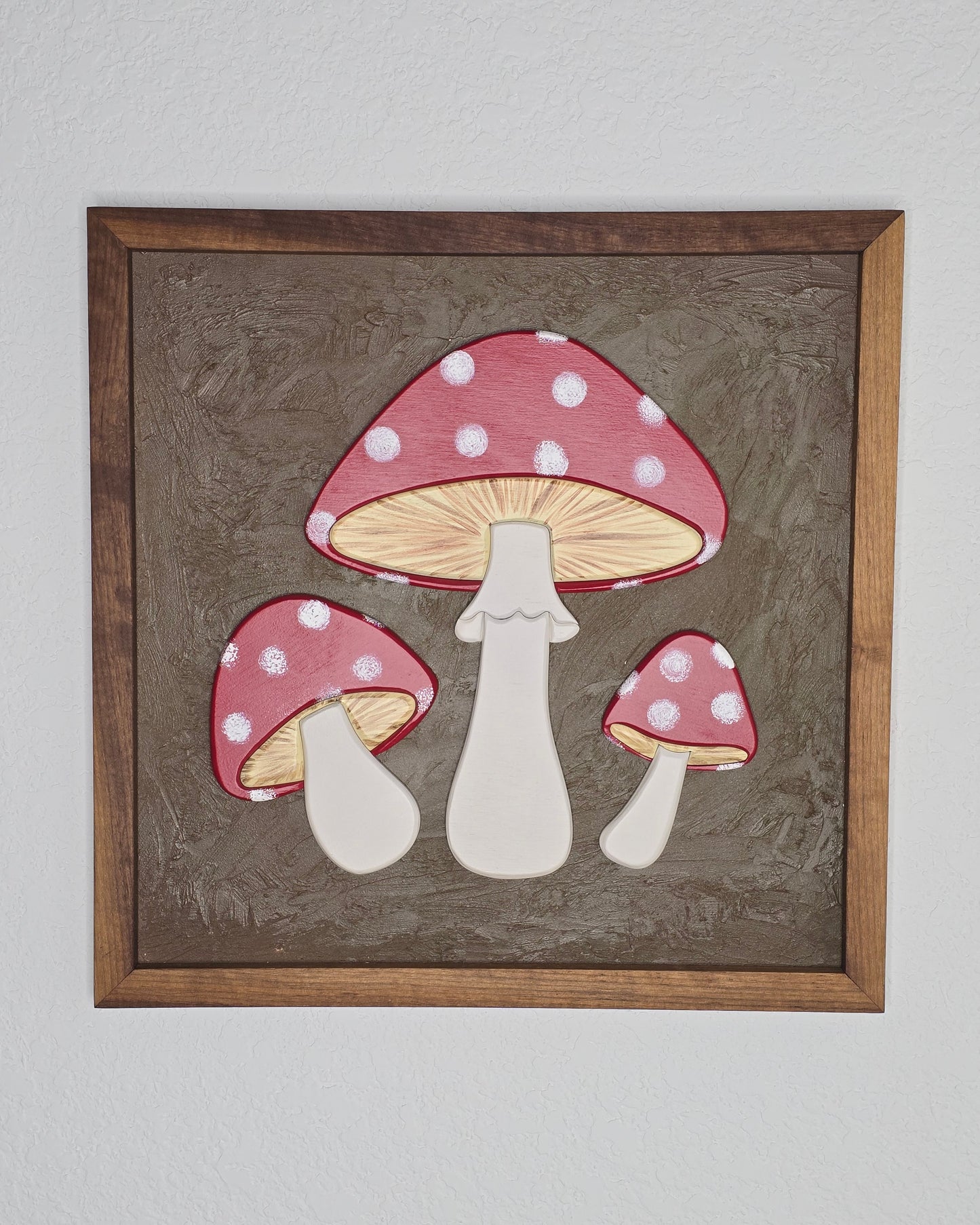 Framed artwork of polka dot mushrooms on a textured brown background
