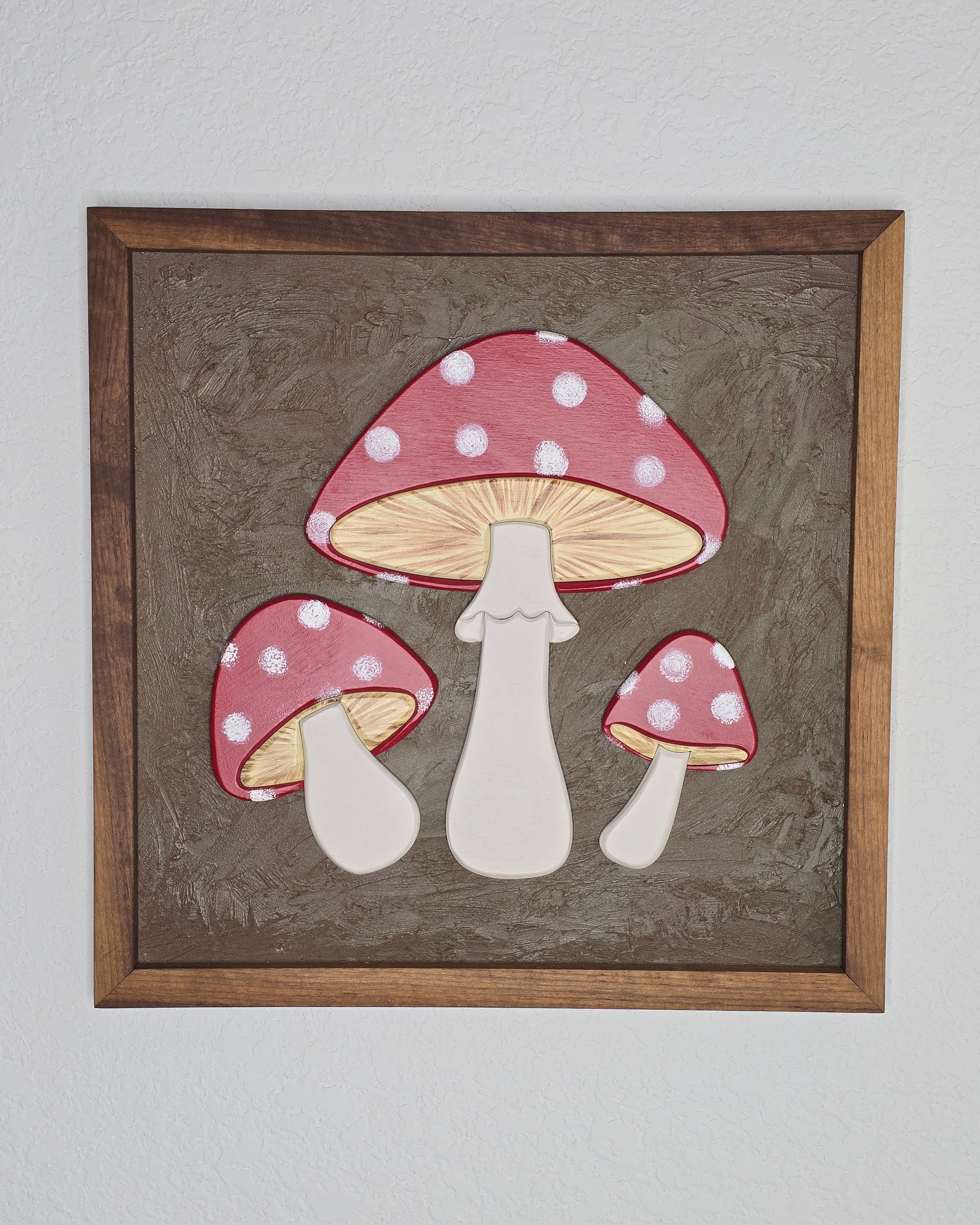 Framed artwork of polka dot mushrooms on a textured brown background