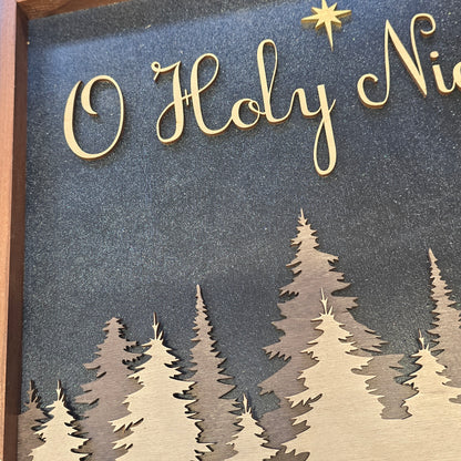 Decorative sign with 'O Holy Ni..' in gold on a blue background with tree cutouts.