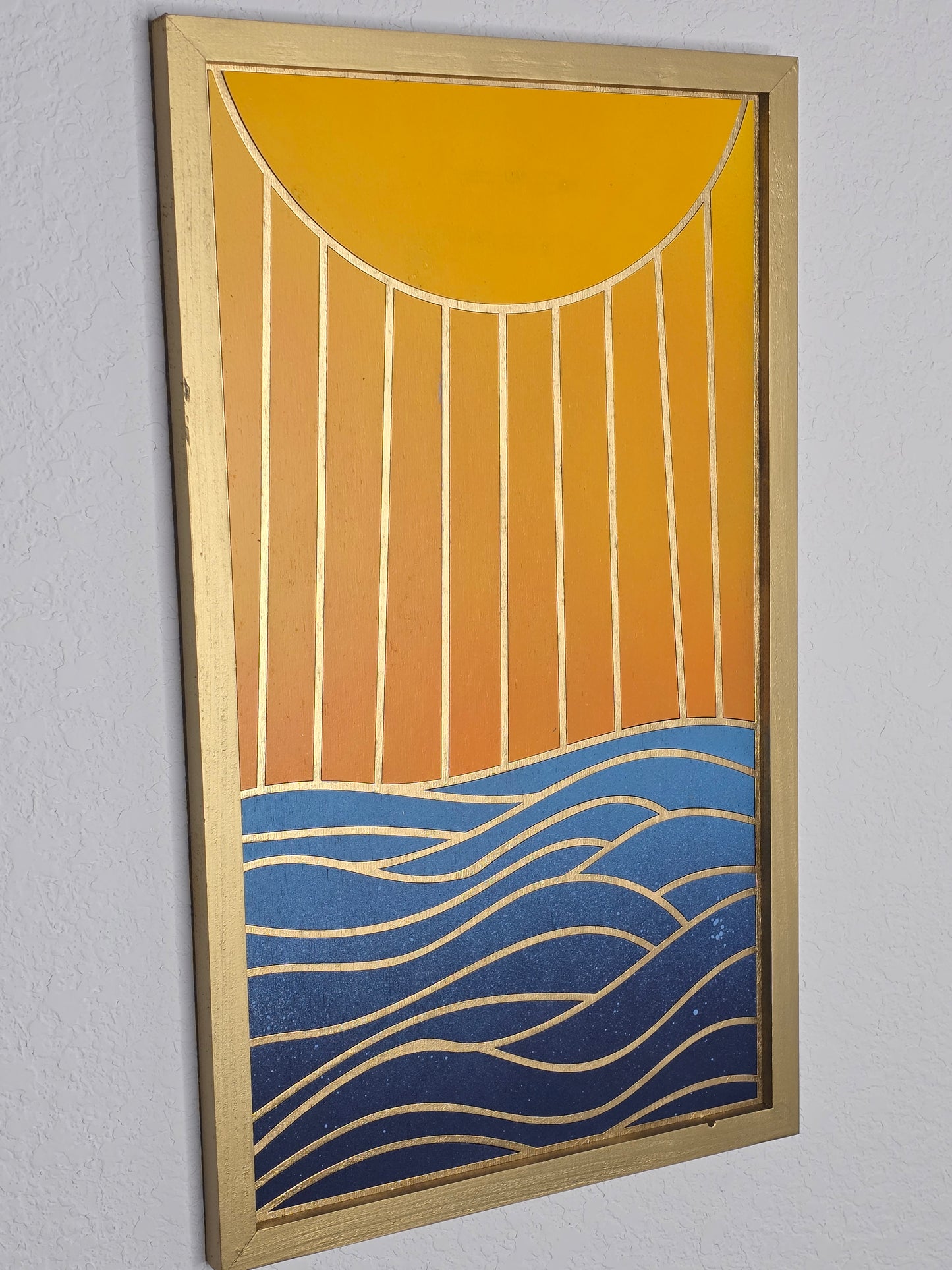 Decorative wall art with abstract patterns in gold, orange, and blue on a gray background