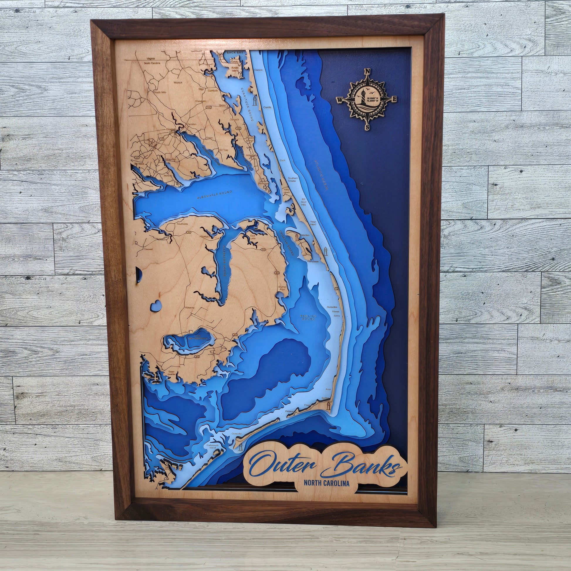 Wooden framed topographic map of Outer Banks, North Carolina on a wooden surface.