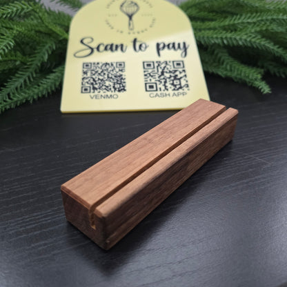 Wooden block with a QR code on a dark surface with greenery