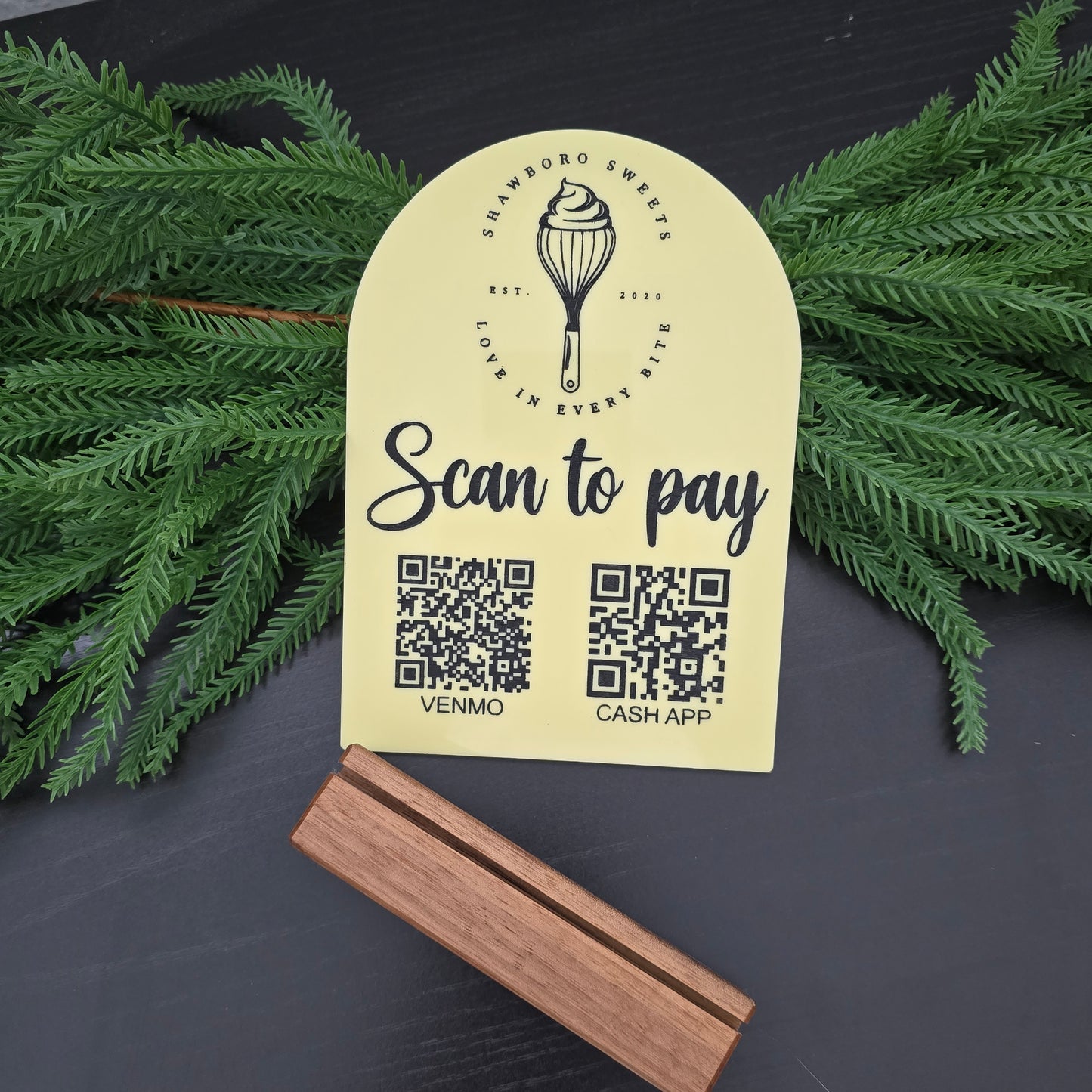 Yellow label with QR codes and branding on a dark surface with greenery