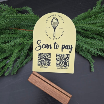 Yellow label with QR codes and branding on a dark surface with greenery