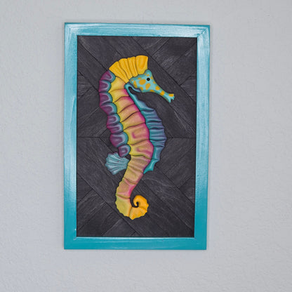 Colorful 3D seahorse wall art featuring vibrant pink, yellow, and teal gradients on a dark wood chevron background with a teal frame.