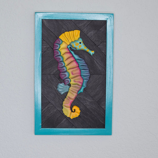 Colorful 3D seahorse wall art featuring vibrant pink, yellow, and teal gradients on a dark wood chevron background with a teal frame.