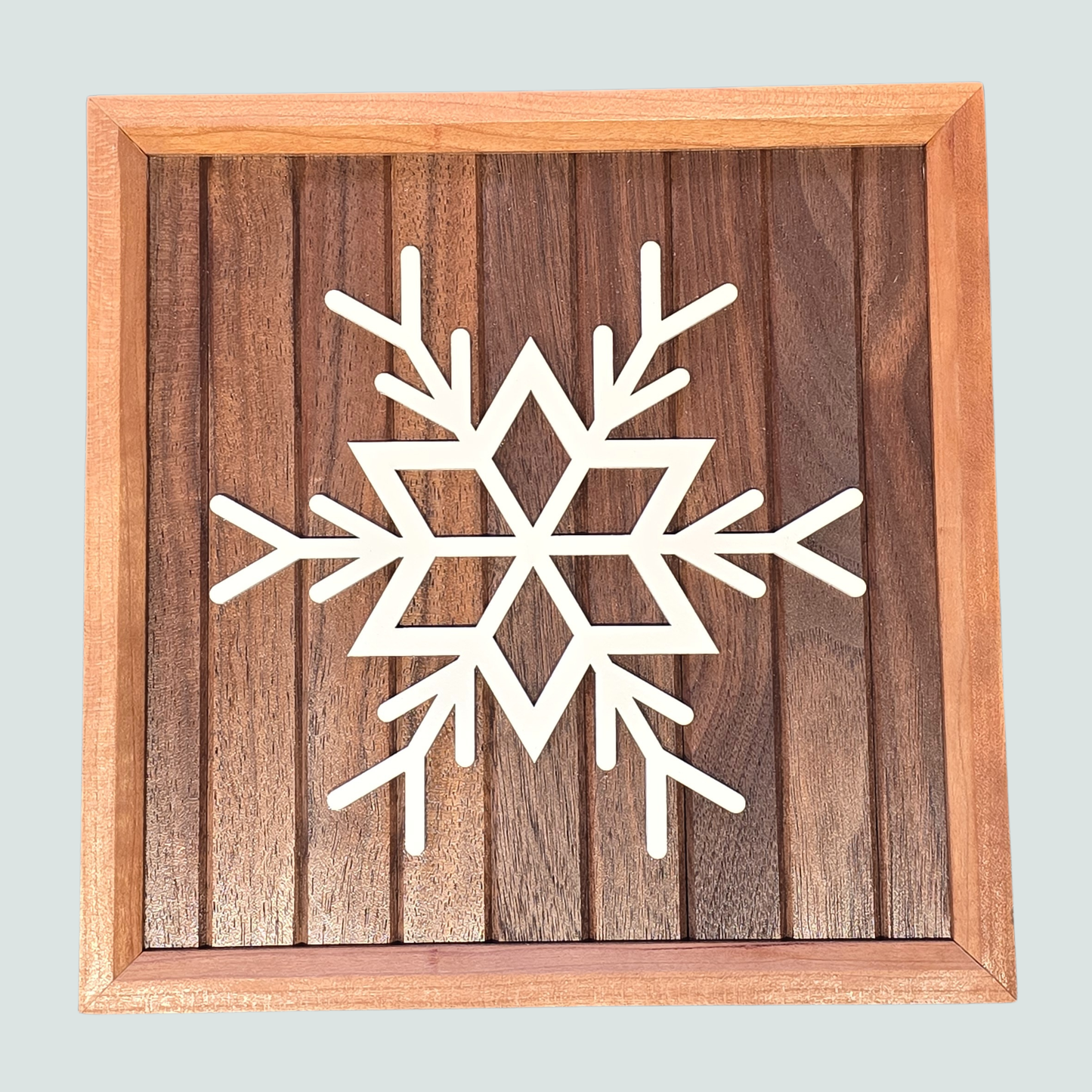 Wooden frame with a white snowflake design on a walnut wood background