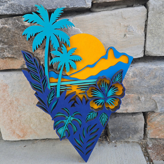 Layered geometric wood art featuring a yellow sunset, teal palm trees, and a tropical hibiscus flower on a textured gray background.