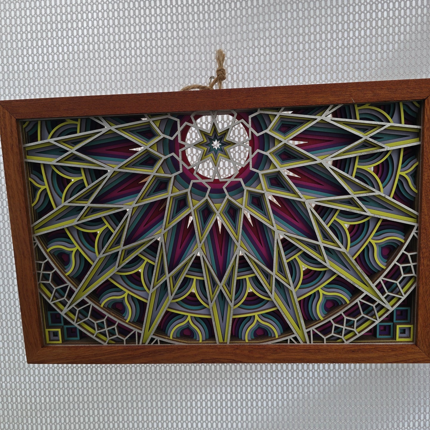Decorative painted panel with geometric patterns in a wooden frame on a textured gray background