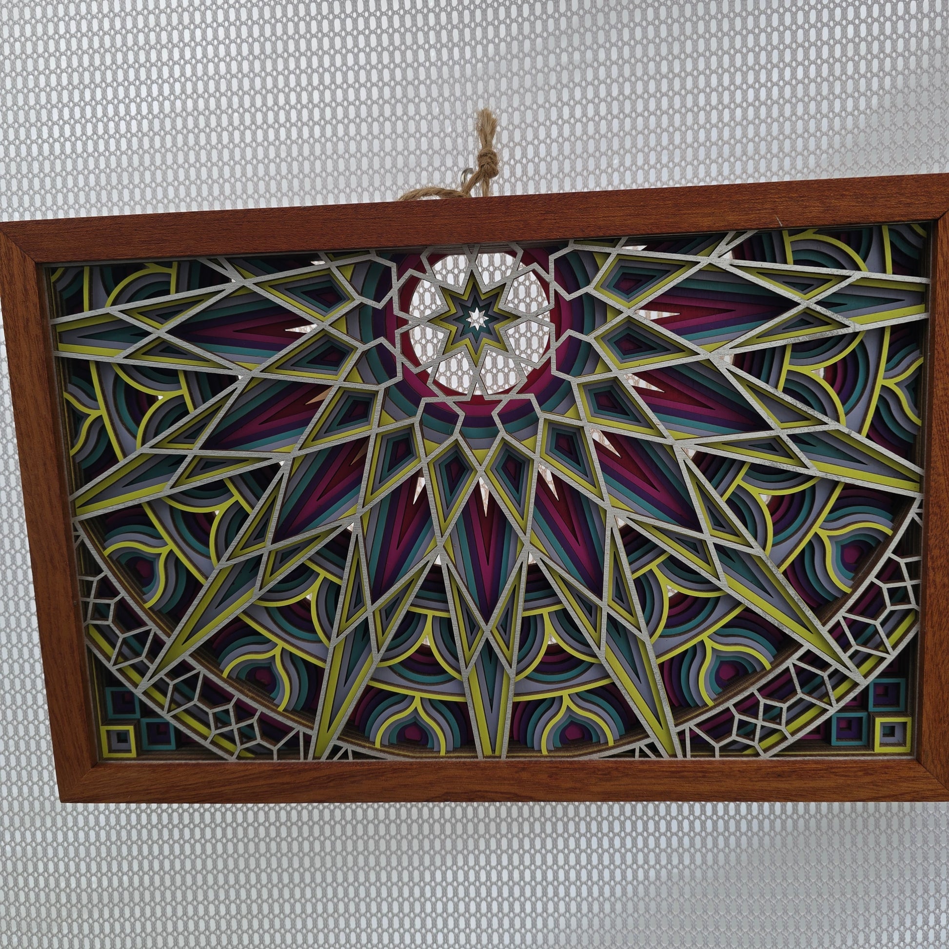 Decorative painted panel with geometric patterns in a wooden frame on a textured gray background