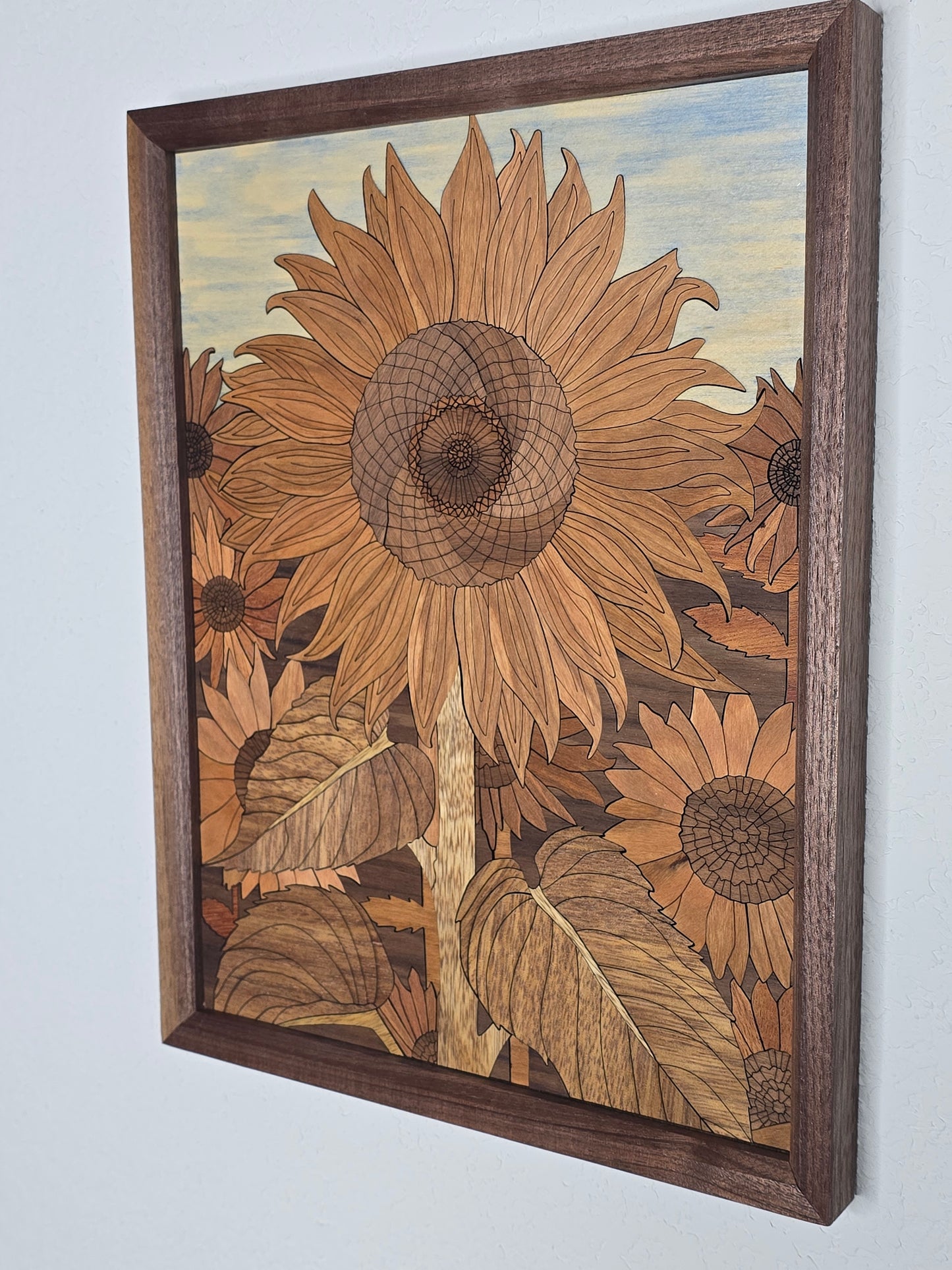 Wooden inlaid artwork of sunflowers in a brown frame on a white background