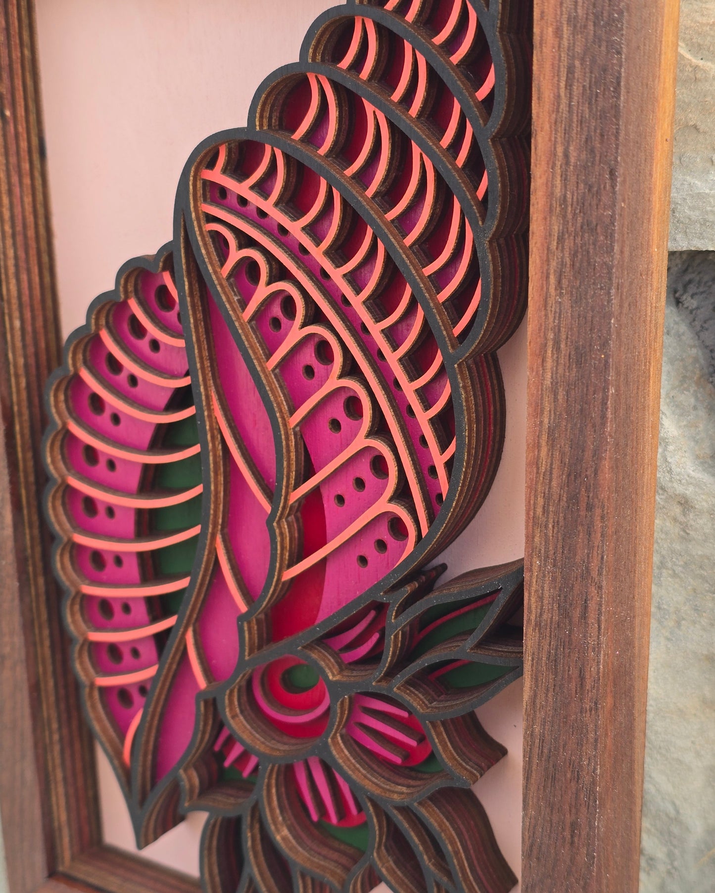 Close-up detail of layered laser-cut wood art showing the depth, geometric patterns, and magenta colors of the "Tidal Bloom" seashell design.