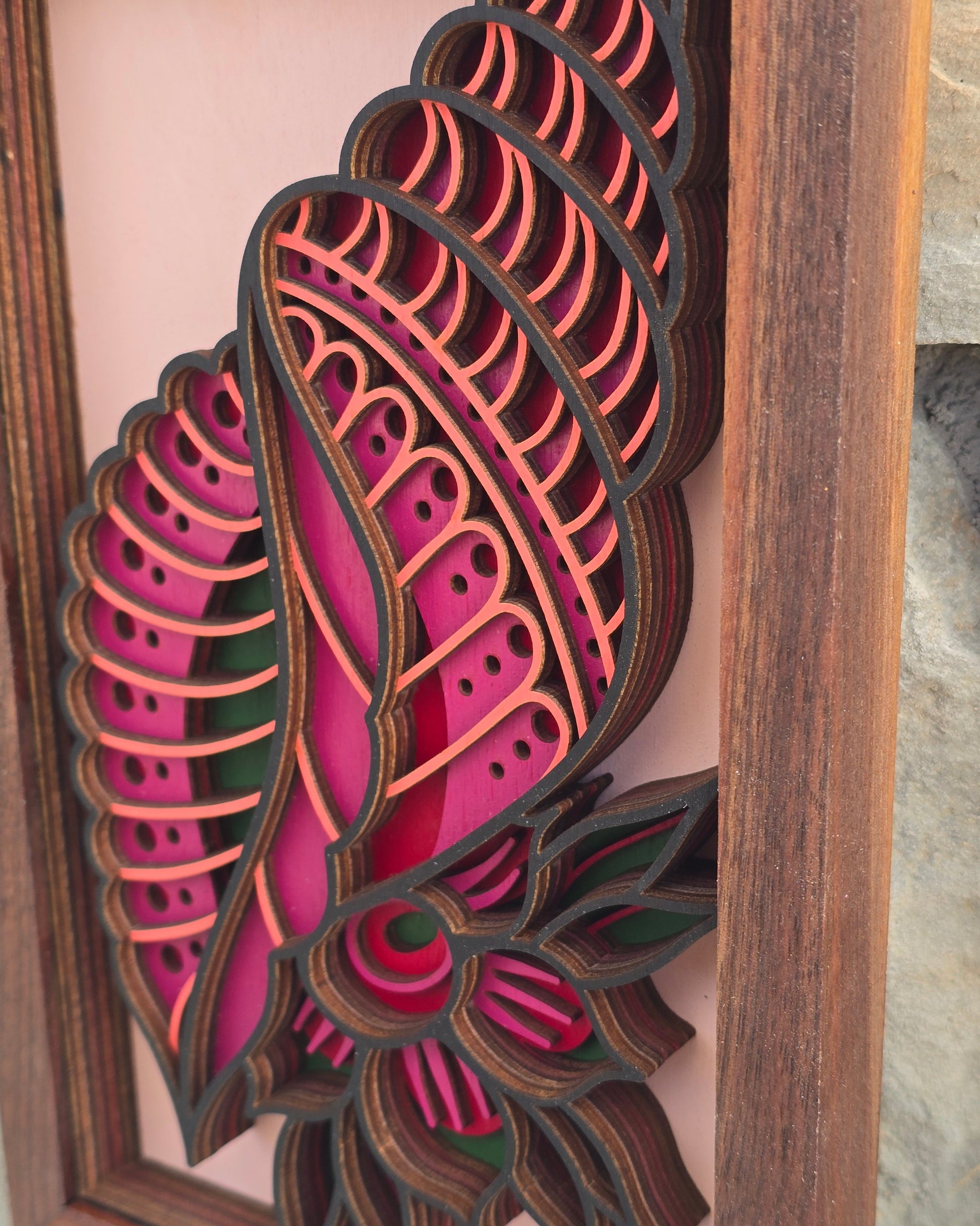Close-up detail of layered laser-cut wood art showing the depth, geometric patterns, and magenta colors of the "Tidal Bloom" seashell design.