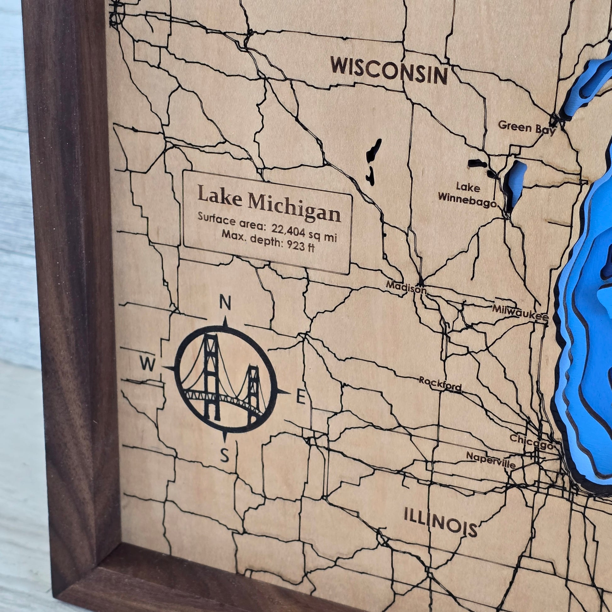 Wooden map of Lake Michigan with engraved details on a wooden frame, upclose shot of the compass rose with the mackinac bridge