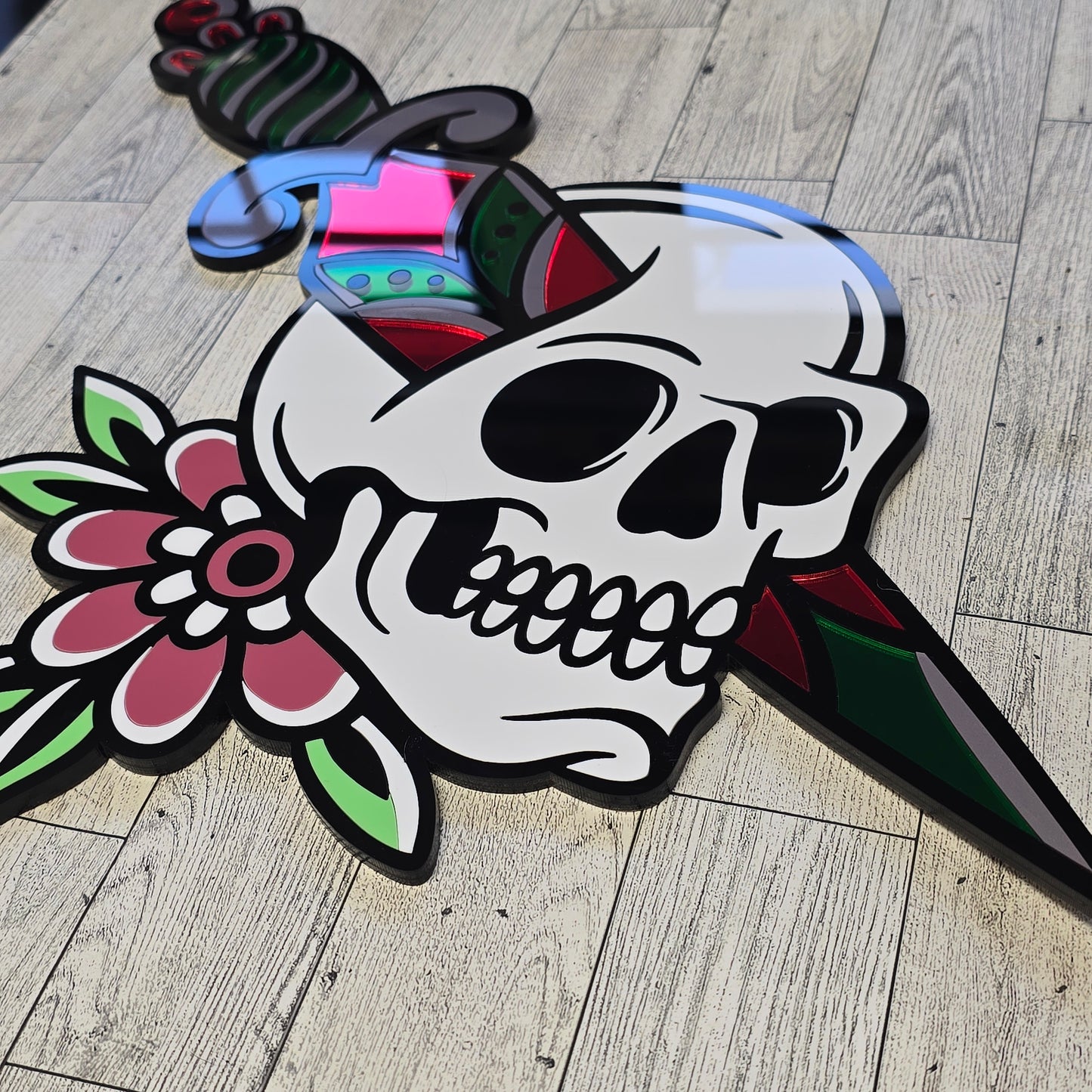Decorative skull design with flowers and knife through skull on a wooden floor.