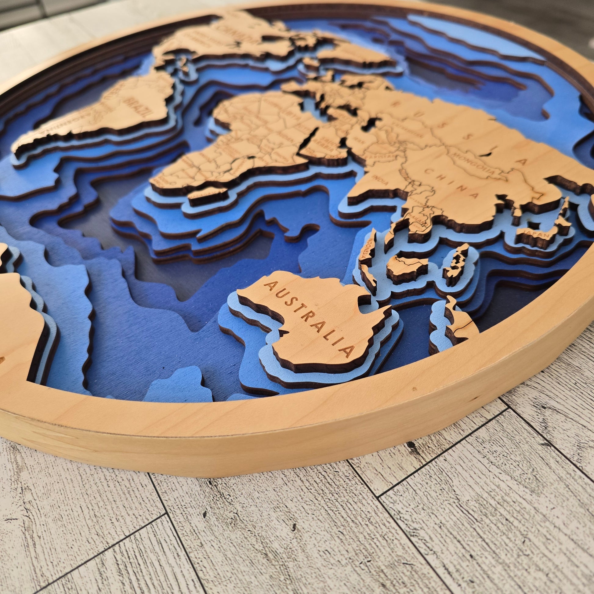3D world map with Australia highlighted on a wooden surface