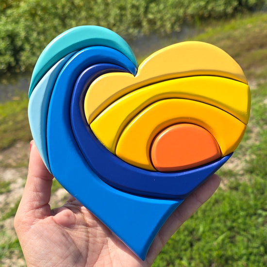 Clip of a heart shape that is carved into waves and a sunset with shades of blues and yellows. 