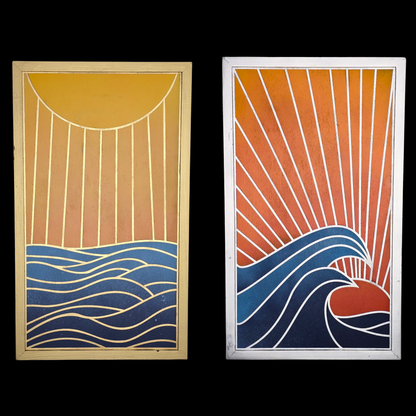 A two-panel vertical wood art set depicting a coastal horizon. The left panel, titled Ocean Sunrise, features a large yellow sun at the top casting long vertical rays over a deep blue sea with calm, gold-outlined horizontal waves, all set in a gold frame. The right panel, titled Ocean Sunset, shows a vibrant red-orange sun dipping below the horizon with dramatic, curling white-capped waves in the foreground and diagonal sun rays filling the orange sky, all set in a silver frame.