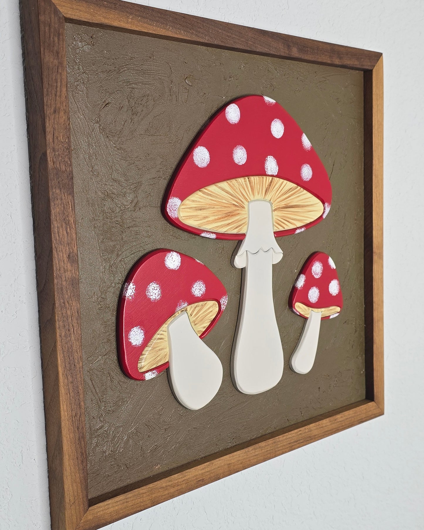 Set of red and white polka dot mushroom-shaped objects on a brown surface with a wooden frame.